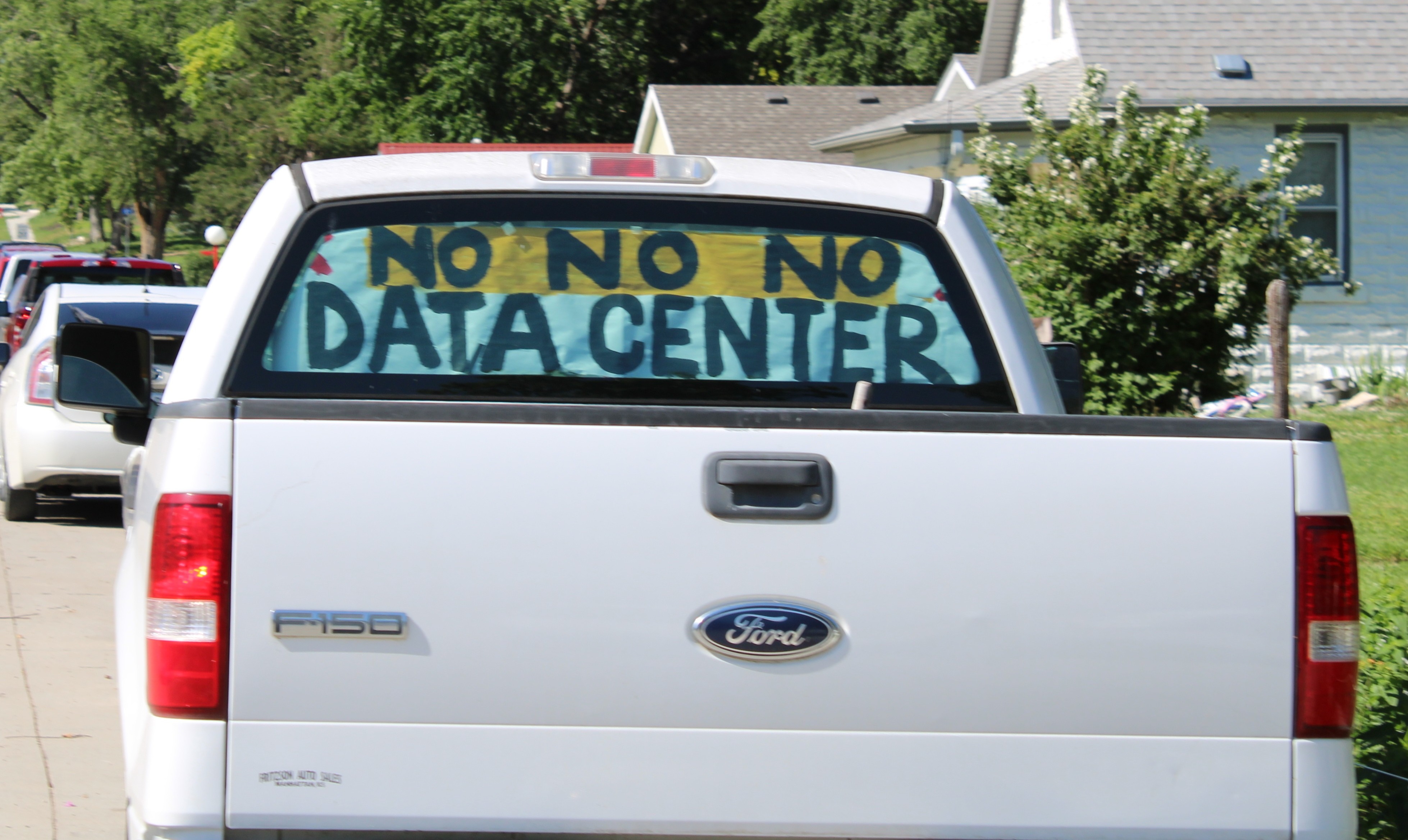 Pickup truck with a NO NO NO DATA CENTER protest sign in the rear window